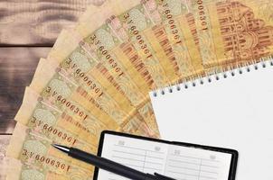 2 ukrainska hryvnias räkningar fläkt och anteckningsblock med Kontakt bok och svart penna. begrepp av finansiell planera och företag strategi foto