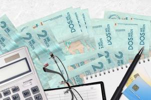 2 colombianska pesos räkningar och kalkylator med glasögon och penna. beskatta betalning begrepp eller investering lösningar. finansiell planera eller revisor pappersarbete foto