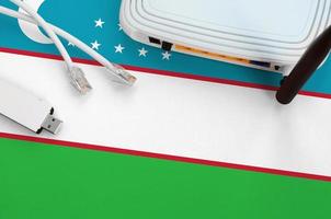 uzbekistan flagga avbildad på tabell med internet rj45 kabel, trådlös uSB wiFi adapter och router. internet förbindelse begrepp foto