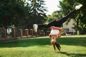 galen stunts. ung kvinna håller på med akrobatisk och parkour knep i de parkera foto