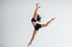 Foto i rörelse. ung sportig kvinna i svart kläder med smal kropp typ i de friska Centrum håller på med övningar
