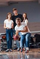 frontvy. unga glada vänner har kul i bowlingklubben på sina helger foto