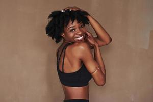 poserar för kameran. ung vacker afroamerikansk kvinna i studion mot brun bakgrund foto