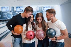 omfamnar varandra. unga glada vänner har kul i bowlingklubben på sina helger foto