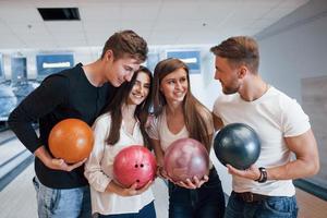 föra konversation. unga glada vänner har kul i bowlingklubben på sina helger foto