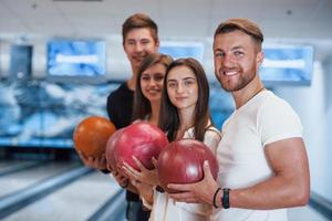 uppriktiga leenden. unga glada vänner har kul i bowlingklubben på sina helger foto