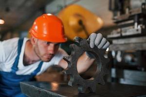 sökande för defekter. man i enhetlig Arbetar på de produktion. industriell modern teknologi foto