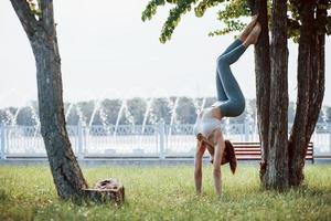 Foto i rörelse. ung kvinna med smal typ av kropp gör övningar i de parkera