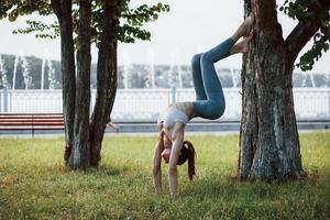 grymt bra flexibilitet. ung kvinna med smal typ av kropp gör övningar i de parkera foto