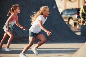 har roligt med bubblor. fritid aktiviteter. två liten flickor har roligt i de parkera foto