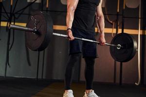 stark man i sportigt kläder lyft skivstång i de Gym foto