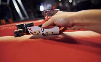 stänga upp se av kvinnas händer. flicka spelar poker spel förbi tabell i kasino och checkar kort foto
