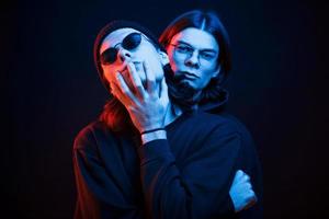 två människor. porträtt av tvilling bröder. studio skott i mörk studio med neon ljus foto