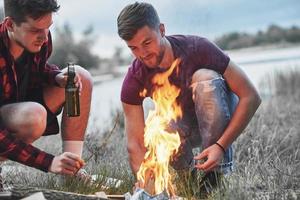 skön brand. grupp av människor ha picknick på de strand. vänner ha roligt på helgen tid foto