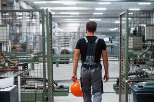 industriell arbetstagare inomhus i fabrik. ung tekniker med orange hård hatt foto