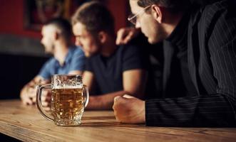 tre manlig vänner i de bar. stödjande ledsen vän. enhet av människor. med öl på de tabell foto