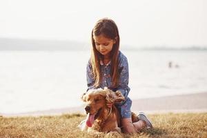 spelar med sällskapsdjur. söt liten flicka ha en promenad med henne hund utomhus på solig dag foto