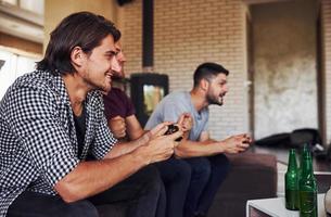 sida se. grupp av vänner ha roligt spelar trösta spel inomhus på levande rum foto