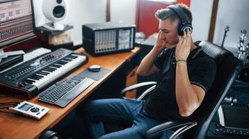 lyssnande till de musik. ljud ingenjör i hörlurar arbetssätt och blandning inomhus i de studio foto