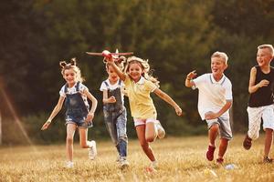 grupp av barn har roligt utomhus med röd leksak flygplan i händer foto