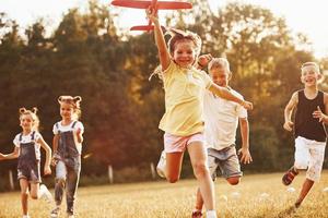 grupp av barn har roligt utomhus med röd leksak flygplan i händer foto