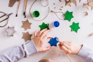 en barn målarfärger en gouache stjärna från kartong för diy jul handgjort dekorationer. topp se. foto