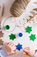 en barn målarfärger en gouache stjärna från kartong för diy jul dekorationer. topp och vertikal se. foto