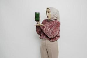 överraskad asiatisk muslim kvinna bär rosa Tröja och hijab som visar kopia Plats på henne smartphone, isolerat förbi vit bakgrund foto