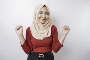 en ung asiatisk muslim kvinna med en Lycklig framgångsrik uttryck bär en hijab isolerat förbi vit bakgrund foto