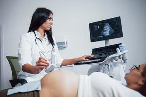 kvinna läkare gör ultraljud för en gravid kvinna i de sjukhus foto