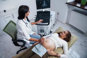 kvinna läkare gör ultraljud för en gravid kvinna i de sjukhus foto