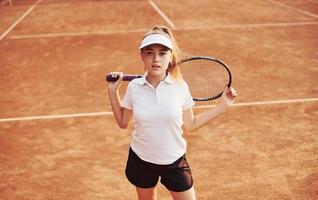 porträtt av ung kvinna tennis spelare i sportigt kläder är på de domstol utomhus foto