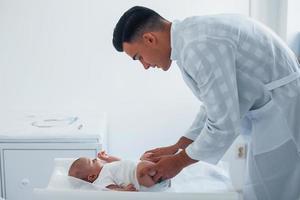 ung barnläkare är med liten bebis i de klinik på dagtid foto