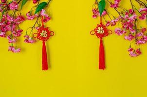 hängande hängen för kinesisk ny år prydnad menande av ord är rikedom med kinesisk blomma blommor på gul bakgrund. foto