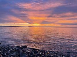 en solnedgång med eldig färger mitt i elektrisk blå över de hav foto