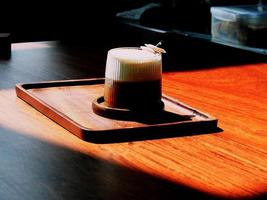 varm kaffe i en kopp på en trä- tabell och de morgon- ljus lyser och de Kafé bakgrund med de gammal trä spannmål. foto