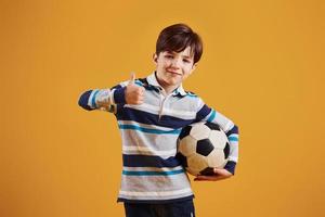 porträtt av ung fotboll spelare med boll. står mot gul bakgrund foto