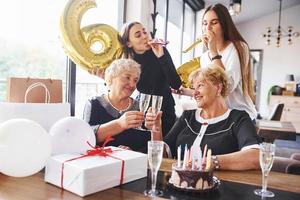 ballonger med siffra 60. senior kvinna med familj och vänner fira en födelsedag inomhus foto