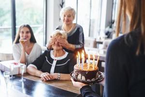 senior kvinna med familj och vänner fira en födelsedag inomhus foto