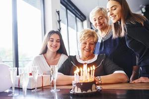 senior kvinna med familj och vänner fira en födelsedag inomhus foto