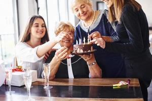 senior kvinna med familj och vänner fira en födelsedag inomhus foto