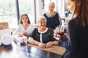 senior kvinna med familj och vänner fira en födelsedag inomhus foto