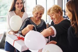 senior kvinna med familj och vänner fira en födelsedag inomhus foto