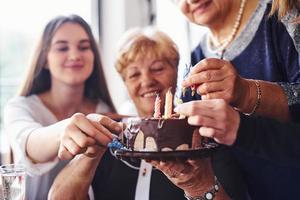 senior kvinna med familj och vänner fira en födelsedag inomhus foto