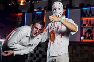 vänner är på de tematiska halloween fest i skrämmande smink och kostymer av zombie foto