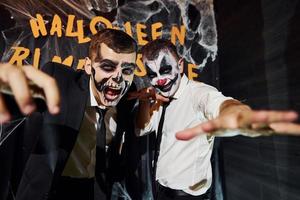 vänner är på de tematiska halloween fest i skrämmande smink och kostymer skrikande till de kamera foto