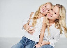 närhet av de människor. mor med henne dotter tillsammans i de studio med vit bakgrund foto