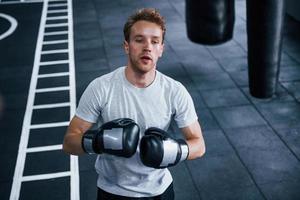 ung man i vit skjorta och boxning skyddande handskar håller på med övningar i Gym foto