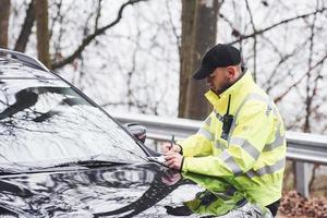 manlig polis officer i grön enhetlig kontroll fordon på de väg foto