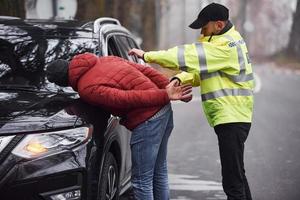 polis officer i grön enhetlig fångad bil stöld på de väg foto